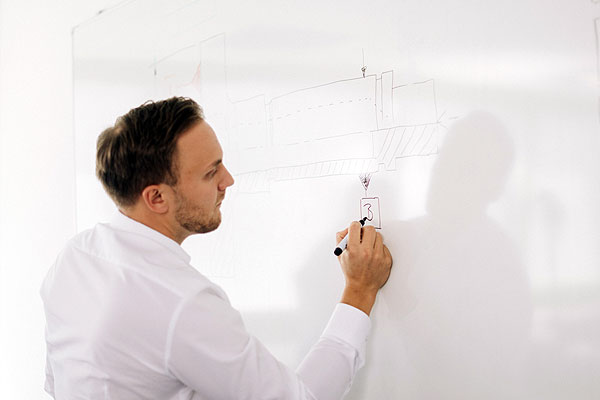 Konstruktionsmethodik Ingenieur skizziert auf einem Whiteboard.