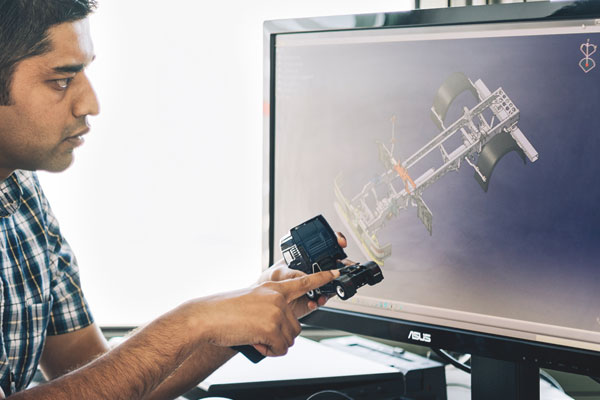 Mechanik Ingenieur gleicht 3D-Modell mit Konstruktionsplan auf Computer ab.