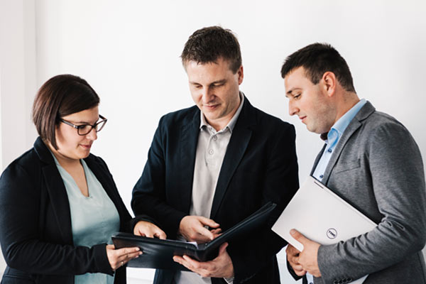 Projektleitung Projektleiter schult zwei Kollegen und sie sehen sich gemeinsam den Projektplan an.